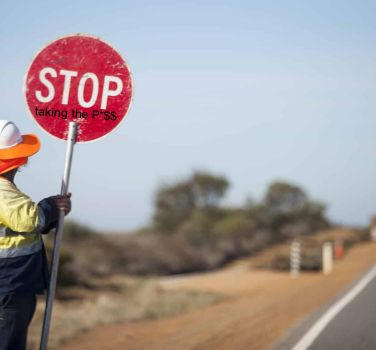 Man holding a stop sign on the side of the road